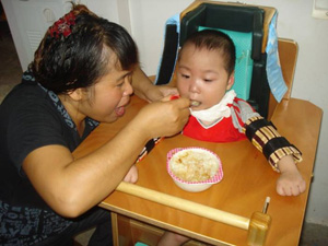 KK sits in the special chair with a good posture for a meal.